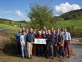 A group of people in front of a green landscape.